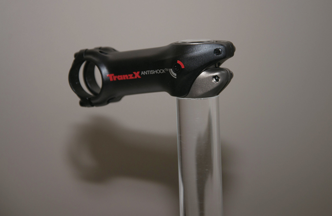 트랜지 X의 안티쇼크 스템 JD-ST129A. 중심부의 핀을 통해 아래로 2도 움직이고, 내부에 고무 소재를 사용해 진동을 흡수한다. 손목과 어깨로 전해지는 피로를 완화시켜준다. T6 6061 알로이로 제작했고, 스템의 각도는 -6도