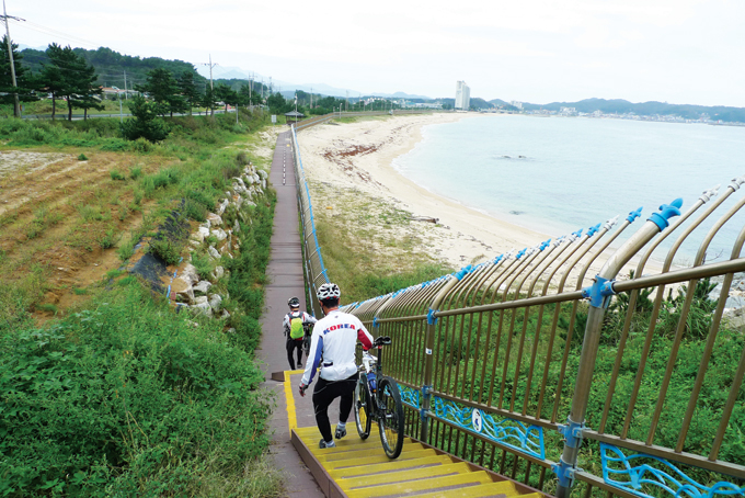 반암해변 근처 철책선과 바짝 붙어 가는 길. 살짝 계단 구간이 있고 멀리 거진항이 보인다.