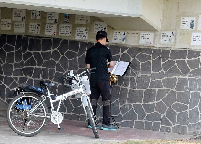 유등천변 한 구석에서 색소폰을 부는 사내. 클레멘타인의 짧은 곡조에도 삑사리가 여럿이니 마나님께 지청구도 한두번 들은 게 아니겠다(대전 서구)