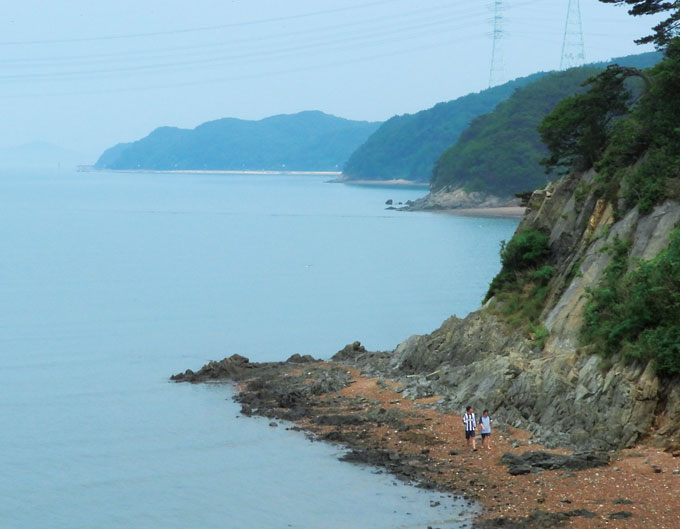 해안도로 중간쯤에서 바라본 대부도 서해안. 물이 들면 갯벌이 사라지고 해안절벽이 강조되어 마치 동해안 같다. 멀리 구봉도 서단의 낙조전망대와 등대가 보인다.