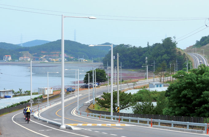 언덕을 구비치며 산뜻하게 나 있는 해안도로. 바닷가 쪽으로 연석으로 분리된 자전거도로가 나 있다.
